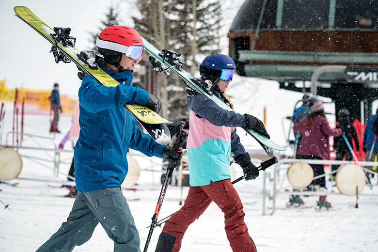 Ski Apparel (carrying skis beside chairlift at resort)